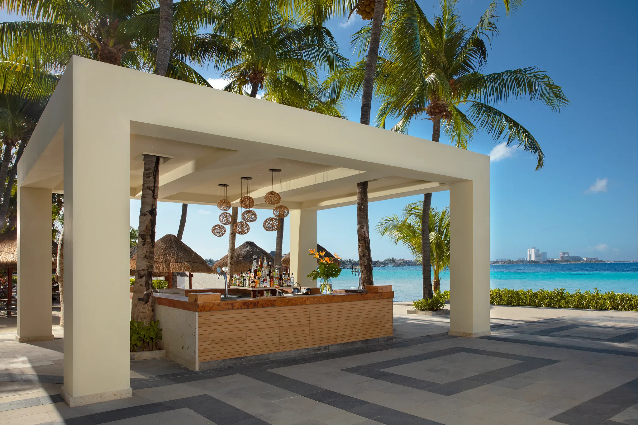 Barracuda beach bar at Dreams Sands Cancun Resort & Spa featuring tropical cocktails, oceanfront seating, and relaxed beachfront ambiance.