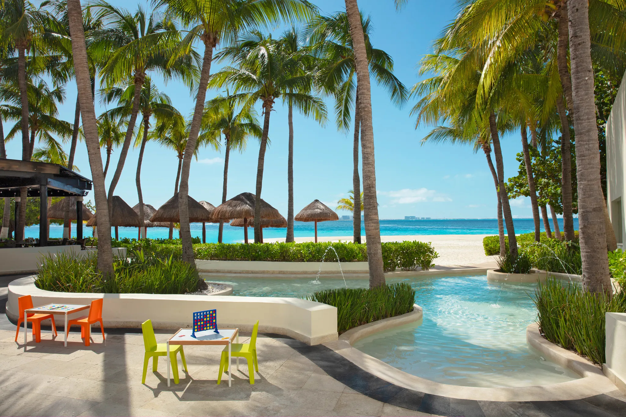 Family-friendly pool and kids activity area with ocean views at Dreams Sands Cancun Resort & Spa.