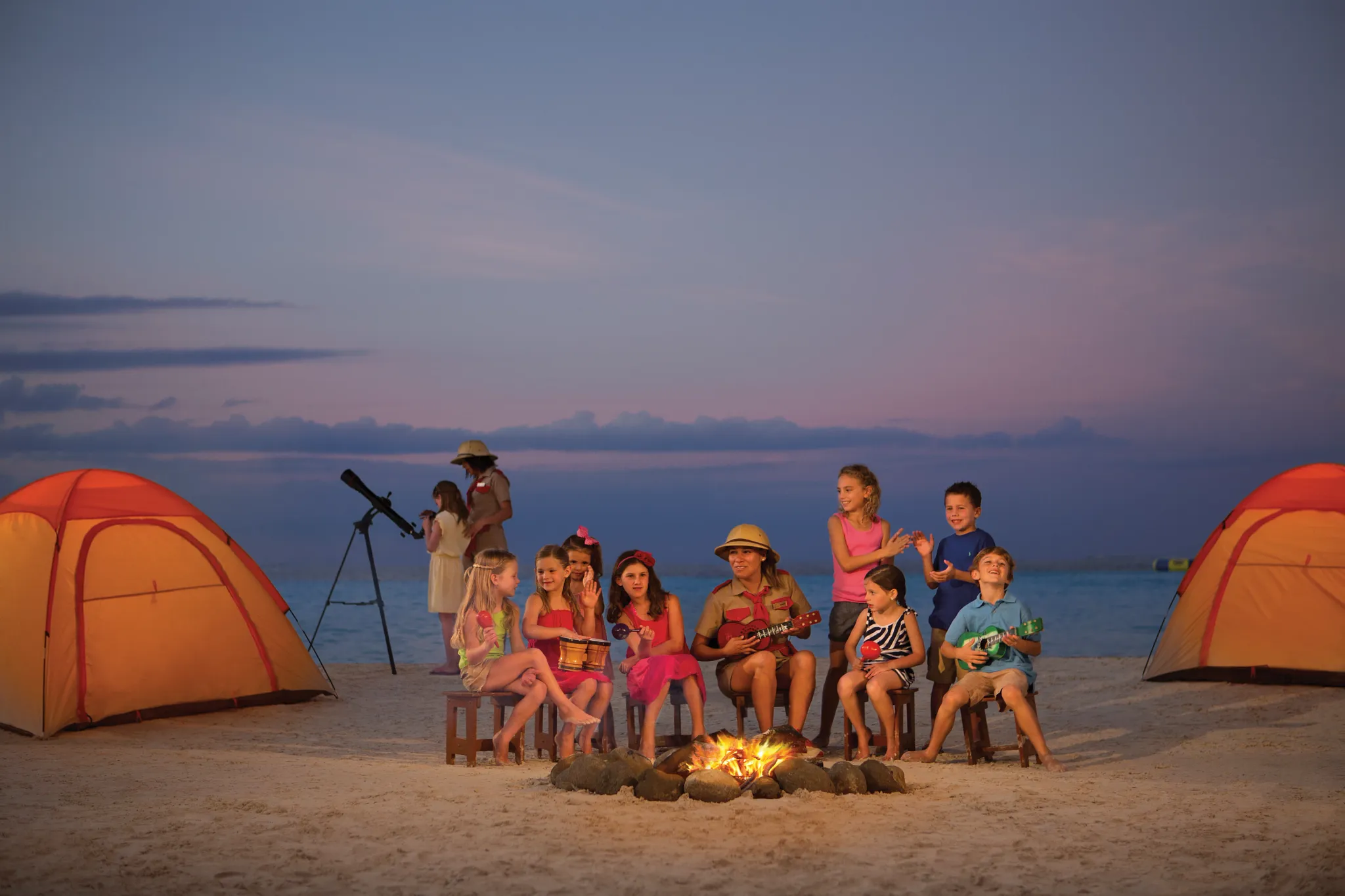 Children and families enjoying a beach campfire and outdoor activities at Dreams Sands Cancun Resort & Spa.
