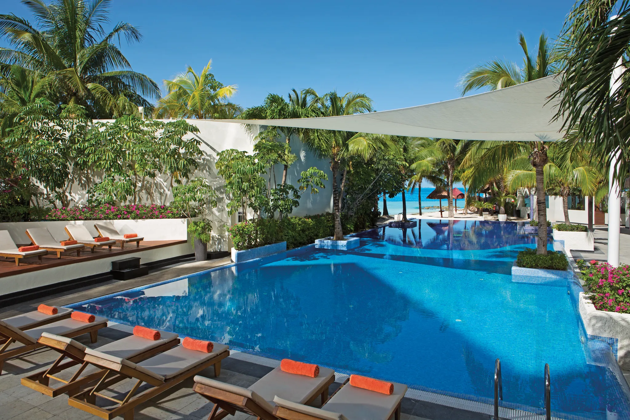 Luxury infinity pool surrounded by tropical landscaping at Dreams Sands Cancun Resort & Spa.