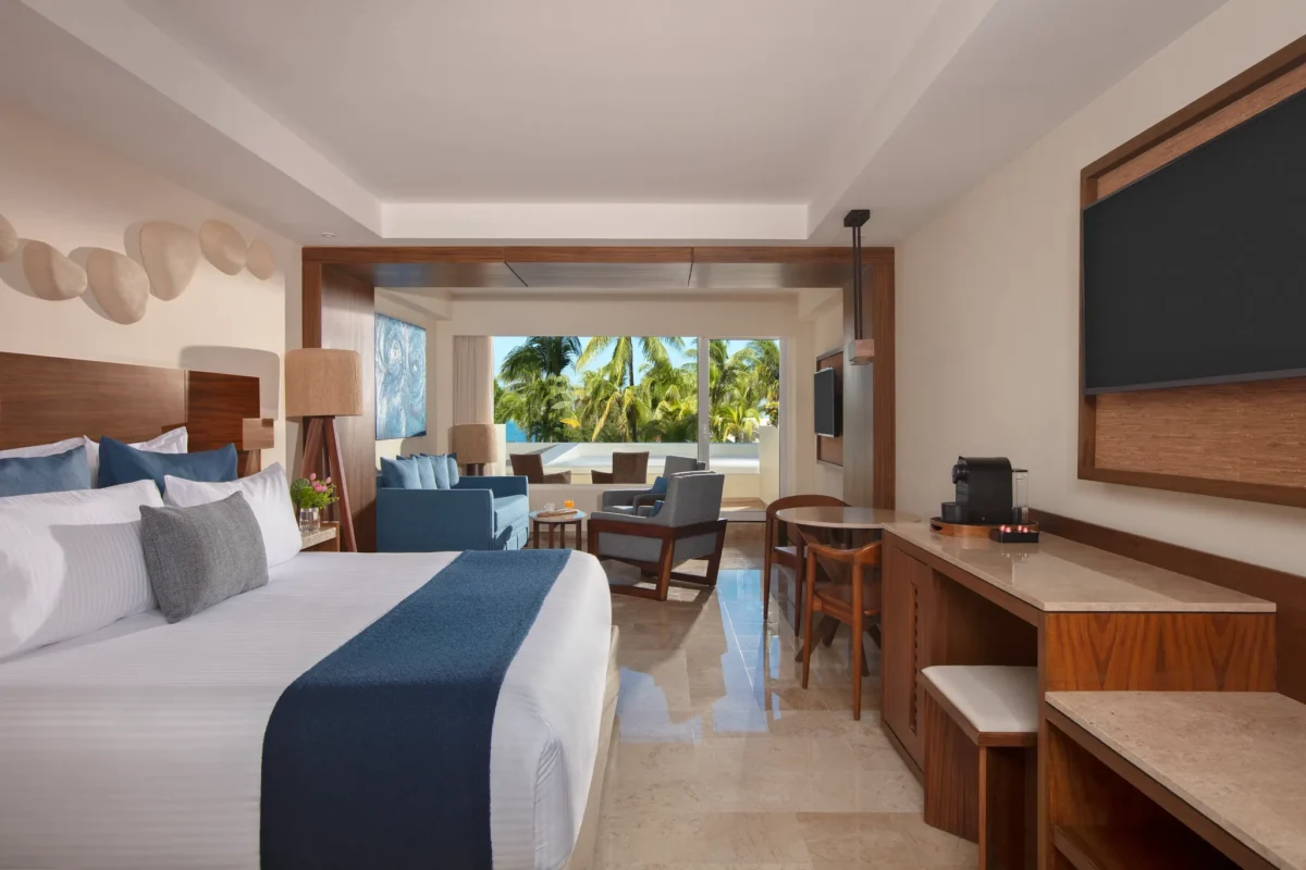 Preferred Club Premium Junior Suite Tropical View with king bed and furnished seating area at Dreams Sands Cancun Resort & Spa.