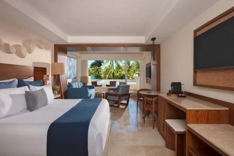 Preferred Club Premium Junior Suite Tropical View with king bed and furnished seating area at Dreams Sands Cancun Resort & Spa.