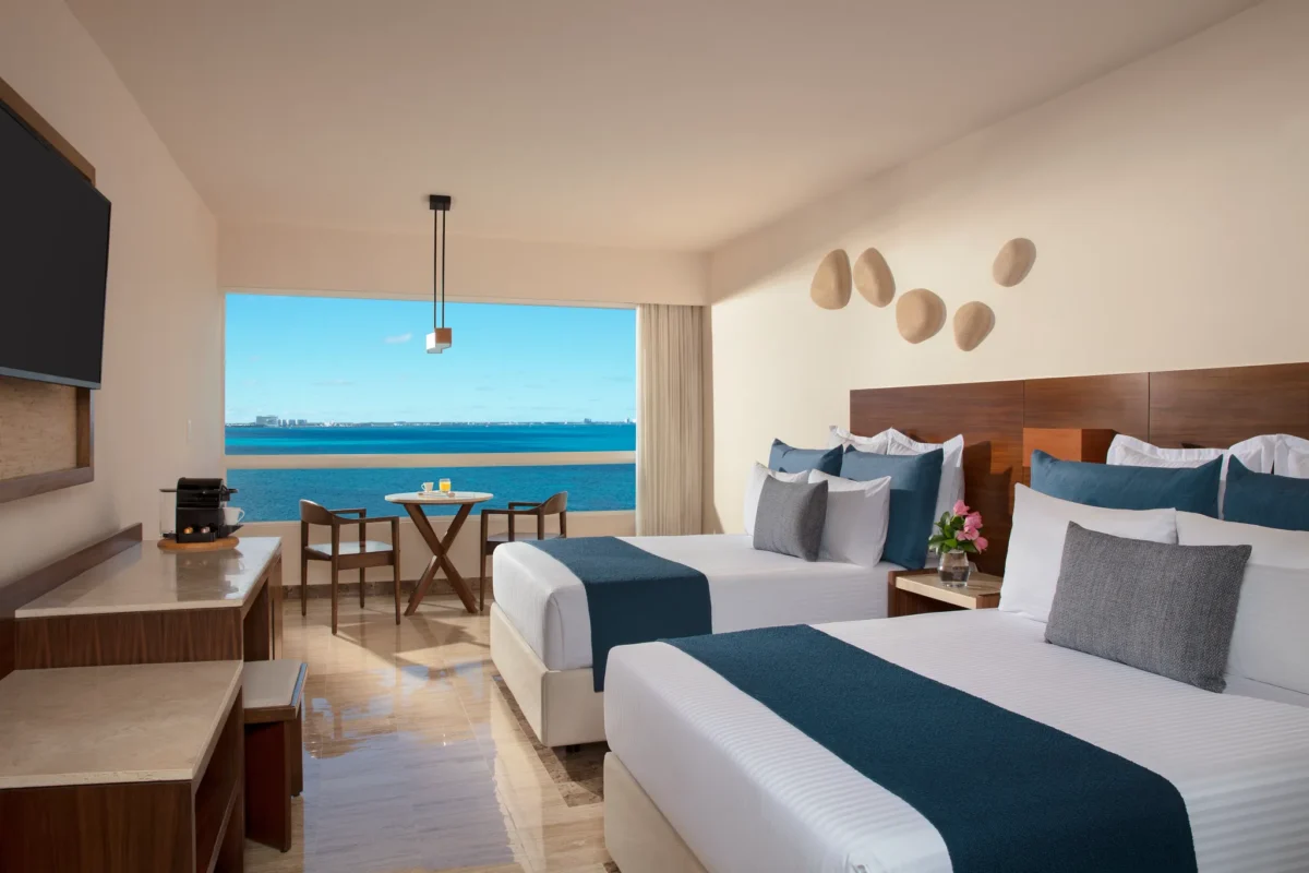 Premium Ocean Front room with two double beds and panoramic Caribbean Sea views at Dreams Sands Cancun Resort & Spa.
